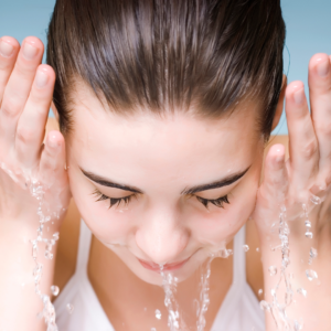 Woman practicing Ayurvedic face washing by splashing water on her face.