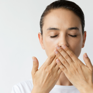 Woman covering her mouth as part of a mindful post-tongue scraping practice for oral freshness.