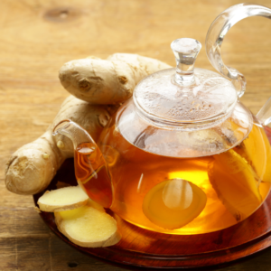 Ginger tea in a glass teapot with fresh ginger slices, a soothing drink to complement a tongue scraping routine.