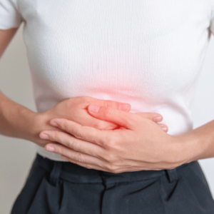 Woman clutching her abdomen with visible inflammation, indicating symptoms of digestive discomfort or chronic inflammation.