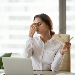 Woman sitting at a desk looking fatigued, representing chronic inflammation effects.