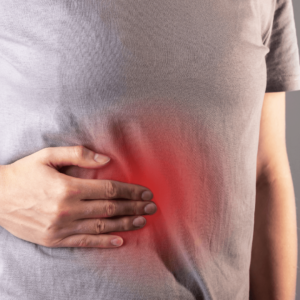 Close-up of a person holding their abdomen with redness indicating gut inflammation.