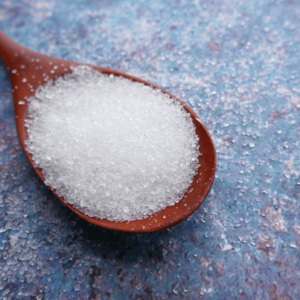 Close-up of refined sugar on a wooden spoon highlighting dietary inflammation triggers.
