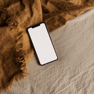 A smartphone on a cozy bed - reducing screen time before sleep helps lower inflammation and improve rest.