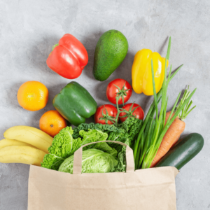 A grocery bag filled with fresh vegetables and fruits.