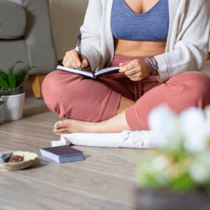 Woman sitting in a cozy space, writing down her goals.