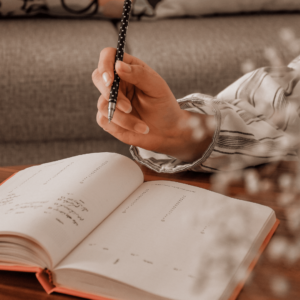 Close-up of a hand holding a pen and writing in a gratitude journal.