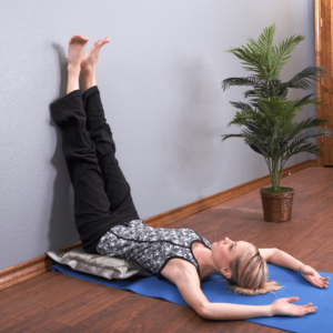 A woman practicing the Legs-Up-The-Wall yoga pose to promote circulation and reduce inflammation.