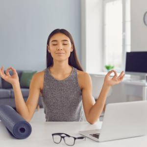 A woman meditating at her desk to stay aligned with her Daily Intentions.