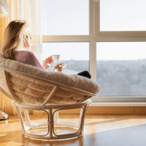 A woman reflecting on her Daily Intentions while sipping tea near a window.