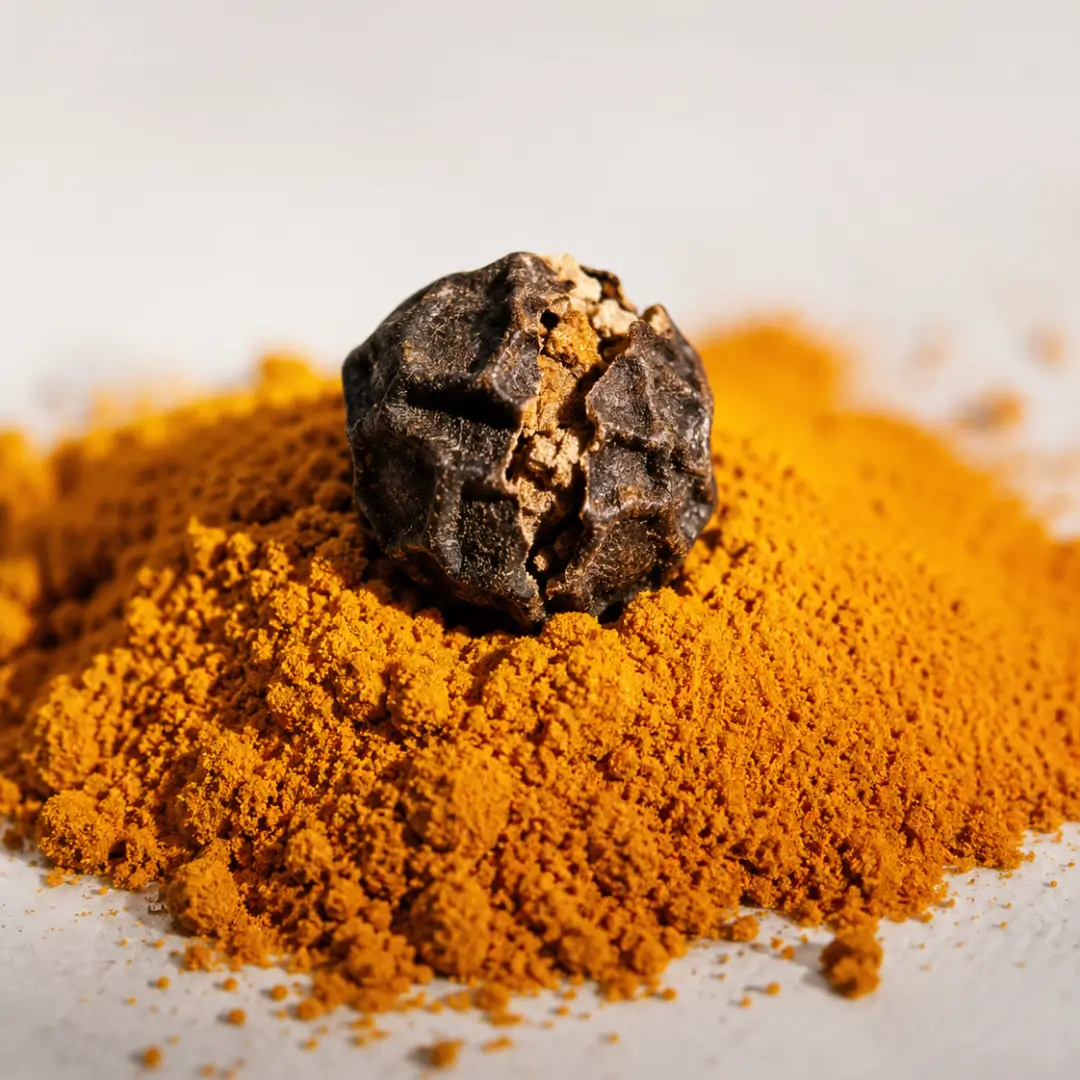 Black peppercorn resting on a mound of golden turmeric powder, representing the piperine and curcumin combination